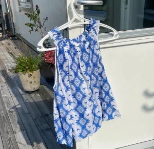 Blåvit broderad linnetopp Holly & Whyte - Säljer en snygg blåvit linnetopp från Holly & Whyte by Lindex i storlek M. Toppen har ett broderat geometriskt mönster i blått på vit botten, är ärmlös och har en rundad hals med rynkade detaljer. Perfekt för varma dagar och sommarhäng!