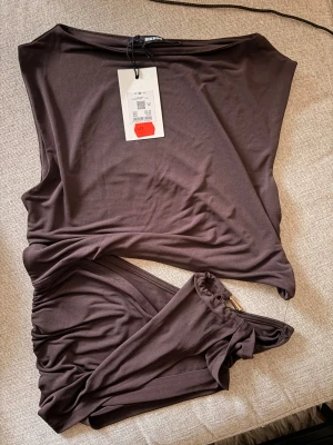Brun topp med guld detalj - Brun topp med gulddetalj. Öppen vid sidan. Aldrig använd, prislappen kvar! 