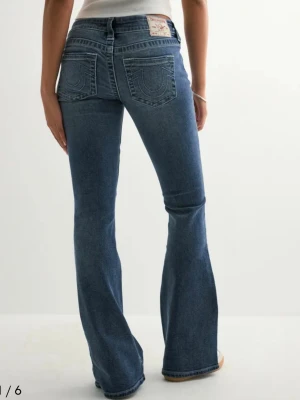True Religion blå bootcut jeans - Säljer ett par blå jeans från True Religion med bootcut-snitt och klassiska kontrastsömmar på bakfickorna. Jeansen har låg midja, fem fickor och en snygg patch med logga bak. Endast använda två gånger. Nypris 1200 