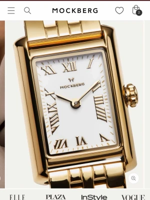 Mockberg klocka guld - Bilderna visar en guldfärgad rektangulär klocka från Mockberg med vit urtavla och romerska siffror, inte en väst.