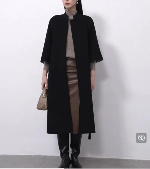 Svart kappa  - Stilren svart kappa med rak passform och trekvartsärm . Kappan har enkel design med knappar framtill och är gjord i mjukt ullmaterial. Perfekt för dig som gillar minimalistisk look och vill ha något som funkar till många outfits.