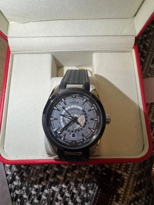 Omega Aqua Terra 150 - New condition with box. Bilderna visar en Omega-klocka med svart gummiband och detaljerad urtavla, men ingen väst finns med.