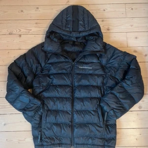 Svart Peak Performance dunjacka - Säljer en svart dunjacka från Peak Performance, fint skick förutom ett hål som är lagat 