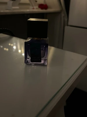 Stilren Eau de Parfum - En elegant Eau de Parfum i en kompakt, modern flaska med mörkt lock. Perfekt för dig som vill ha en stilren accessoar på sminkbordet. Märke och volym framgår ej.