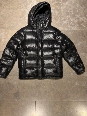 Svart Ralph Lauren Shiny Puffer - Svart Ralph Lauren Pufferjacka i jättefint skick, riktigt varm att ha nu till kalla vintern. Storlek M herr men funkar även som typ en L på tjejer eller oversize. Skriv gärna för frågor