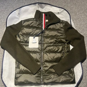 Olivgrön Moncler cardigan  - Hej säljer denna moncler cardigan som jag haft ett tag, väldigt snygg och extremt bra skick🤩säljer den för jag vill köpa nånting annat. Såg ett par likadana ute för mellan 5-8 tusen och nypris är extremt mycket dyrare än mitt pris, så riktigt bra kap😁 Mitt pris är 2700 men vid en snabb och smidig affär så kan jag släppa lite billigare helt äkta går att scanna ärmen och inom tröjan. Hör av dig vid frågor!