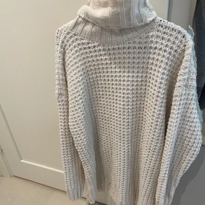 Vit stickad polotröja i oversized modell - Säljer en chunky vit stickad polotröja med oversized passform. Tröjan har grovstickat mönster och hög polokrage som ger en riktigt mysig vibe. Perfekt för kyliga dagar och enkel att styla med jeans eller leggings.väldigt stor, kan användas som klänning