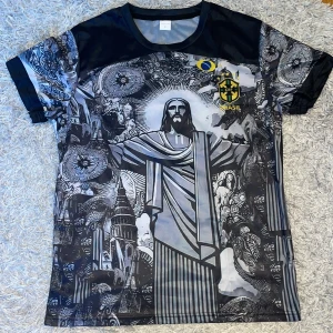 Brasil fotbollströja svart/grå S - Unik Brasilien fotbollströja i svart och grått med stort grafiskt tryck av Kristusstatyn och detaljerade mönster. CBF Brasil-logga och brasiliansk flagga på bröstet. Tillverkad i lätt, andasvänligt syntetmaterial. Rund hals och korta ärmar.