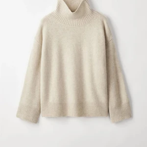 Beige polotröja i kashmir - Supermjuk beige polotröja i kashmir med oversized passform och bred ribbstickad krage. Tröjan har långa ärmar och ribbade muddar vid ärmslut och nederkant. Perfekt för lager-på-lager och chill höst- och vinterstil. Knappt använd från Soft Goat. Denna färgen Natural Sand finns inte längre i denna modell. 