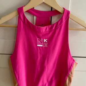 Rosa träningstopp från Nike - Säljer en sportig och snygg rosa träningstopp från Nike Perfekt för gymmet eller löprundan! 