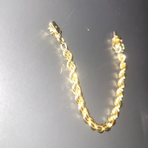 Guldarmband med tvinnad kedja - Säljer ett snyggt armband i guld med tvinnad kedja och robust lås. Armbandet har en klassisk och stilren look som passar perfekt till dig som gillar att sticka ut med accessoarer. Perfekt att matcha med andra smycken för en personlig stil.