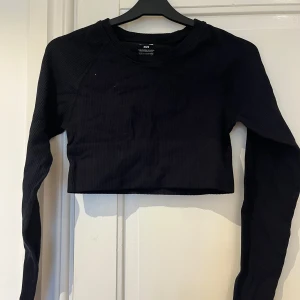 Svart croppad långärmad topp BikBok - Svart ribbad croppad topp från BikBok med lång ärm och rund halsringning. Tillverkad i stretchigt material som sitter snyggt och bekvämt. Jag har haft den både på gymmet och till vardags, osäker på material 