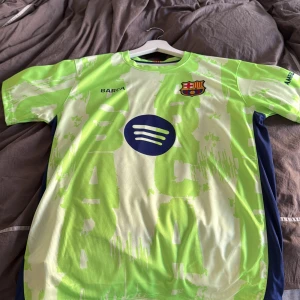 Barcelona Lamine Yamal #10 fotbollströja - Snygg Barcelona fotbollströja med Lamine Yamal och nummer 10 på ryggen. Tröjan är kortärmad och har en ljusgrön och vit färg med ett abstrakt mönster. FCB-emblemet på bröstet, Spotify-logga och UNHCR-tryck. Tillverkad i lätt polyester för maximal komfort. Köpt för 3 dagar sedan.