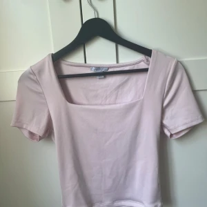 Ljusrosa topp med fyrkantig ringning Amisu - Säljer en ljusrosa topp från Amisu i storlek L. Toppen har korta ärmar och en snygg fyrkantig ringning framtill. Tillverkad i mjukt och stretchigt material som sitter skönt på kroppen. Perfekt för dig som gillar en enkel men trendig look.