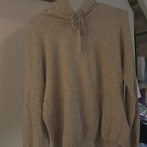 Beige stickad hoodie med snören - Mysig beige stickad hoodie med huva och snörning framtill. Perfekt för lager-på-lager och chill dagar! Jätteskönt material och så mysig inför hösten🥰🥰