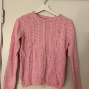 Rosa kabelstickad tröja från GANT - Supersöt rosa kabelstickad tröja från GANT med broderad logga på bröstet. Tröjan är knappast använd och en superfin stilren tröja till alla tillfällen!💞💞💞
