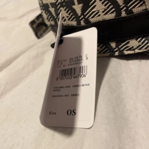 Salvatore Ferragamo mönstrad keps - Snygg keps från Salvatore Ferragamo med svart och beige grafiskt mönster över hela kepsen. Justerbar rem med metallspänne bak och en svart läderdetalj med logotypen på sidan. Tillverkad i 100% bomull, perfekt för dig som gillar exklusiva accessoarer.