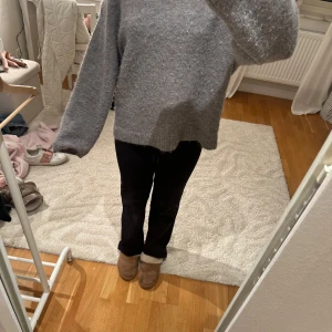 Grå stickad tröja med lång ärm - Mysig grå stickad tröja med lång ärm och avslappnad passform. Tröjan har en enkel design med ribbade muddar vid ärmslut och nederkant. Perfekt för kyliga dagar och enkel att matcha med olika outfits.