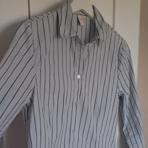 🤩 Sjukt snygg skjorta!! 🤩 - Snyggaste skjortan jag äger men säljer för den tyvärr är för liten och säljs inte längre.          Storlek 36, väldigt slim fit vid midjan, svänger ut lite under midjan för att se ännu mer slim ut när man har den på sig.💕                Ljusblå är den med svart/grå/mörkblå färg på ränderna! 🩷Använt den bara någon enstaka gång så den är som ny förutom att lappen ej sitter kvar.                                            Orginal pris: 399