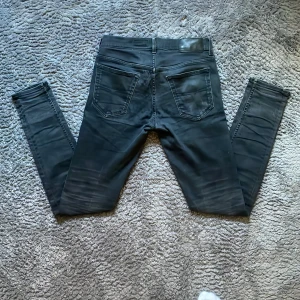 Svarta slim jeans från tiger of Sweden - Svarta jeans från Tiger of Sweden i slim fit-modell. Jeansen har klassisk femficksdesign, smala ben och snygga detaljer vid fickorna. Tillverkade i italienskt denimtyg och passar perfekt för dig som gillar en stilren och modern look.