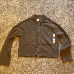 Brun stickad overshirt med dragkedja - Säljer en brun stickad overshirt från Åhlens med två stora fickor framtill och hel dragkedja. Jackan har klassisk krage och lång ärm, perfekt för lager-på-lager. Enkel och stilren design som funkar till många outfits.