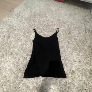 Svart linnetopp från 157, XS - Enkel svart linnetopp från 157 med smala axelband. Toppen är i mjuk bomull med lite stretch för en bekväm passform. Perfekt att styla med jeans eller kjol för en clean look.