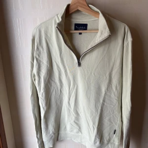 Ljusbeige half zip tröja Bondelid - Snygg ljusbeige långärmad tröja från Bondelid med half zip-dragkedja och hög krage. Tillverkad i mjuk bomull, perfekt för lager-på-lager. Enkel och stilren design som funkar till det mesta.