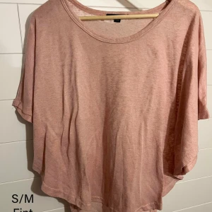 Ljusrosa loose topp från H&M - En supermjuk och luftig ljusrosa topp från H&M med rund halsringning och korta, vida ärmar. Perfekt för en avslappnad stil och enkel att matcha med jeans eller kjol. 