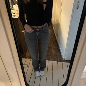 Grå raka jeans från Zara, stl 34 - Säljer ett par grå jeans från Zara i storlek 34. Jeansen har rak passform, klassisk femficksdesign och normal midja. Tillverkade i bomull med en snygg tvättad grå färg som passar till det mesta. Perfekta för en avslappnad och trendig look.