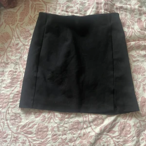 Svart kortkjol från Stradivarius X - Enkel och stilren svart kortkjol från Stradivarius i storlek XS. Kjolen har en rak passform och är tillverkad i ett mjukt material som känns bekvämt. Perfekt att matcha med en crop top eller stickad tröja för en snygg look.