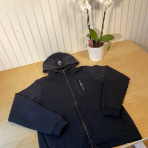 Svart Sail Racing Fleece  - Säljer en svart Sail Racing kofta. Den saknar en dragkedja på högra delen av koftan som man ser klart och tydligt på sista bilden. Den har inga mer skador än det. Jag säljer den på grund av att den är för stor på mig. 