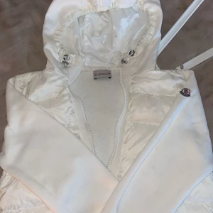 Vit pufferjacka från Moncler med luva - Säljer en snygg vit pufferjacka från Moncler med huva och dragkedja. Jackan har Moncler-logga på ärmen, qr kod finns i jackan🤍