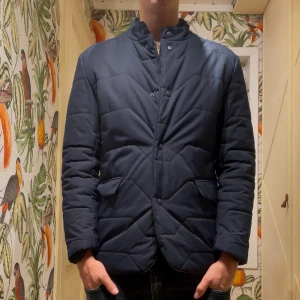 Mörkblå quiltad dunjacka - Nu finns denna snygga och stilrena dunjacka ✅ Skicket är 8/10. Den är använd men har inga defekter. En perfekt jacka inför den kalla hösten och början av vintern ! Tveka inte att höra av dig ✅ 