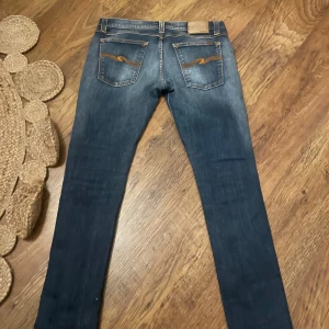 Nudie Jeans  - Säljer ett par Nudie Jeans Tight Long John i färgen Super Blue. De är slimma jeans med klassisk femficksdesign, snygga kontrastsömmar och broderade bakfickor. Jeansen är tillverkade i bomull och har en tight passform med låg midja.