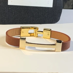 Brunt armband från Luce D'Oro - Snyggt armband från Luce D'Oro med brunt band och guldfärgade metalldetaljer. Stilren design med elegant spänne och diskret struktur på bandet. Perfekt accessoar för att lyfta din outfit med en touch av italiensk känsla.