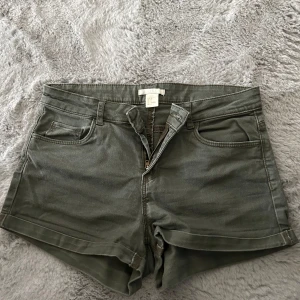 Gröna jeansshorts från H&M - Snygga gröna jeansshorts från H&M i klassisk femficksmodell. De har uppvikta benslut, dragkedja och knapp framtill samt bälteshällor. Perfekta för varma dagar och enkla att matcha med allt. Stl 36.
