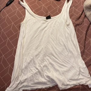 Vit linnetopp från Gina Tricot XS - En enkel och stilren vit linnetopp från Gina Tricot i storlek XS. Toppen har smala axelband och är tillverkad i mjuk bomull, perfekt för varma dagar eller som lager under andra plagg.