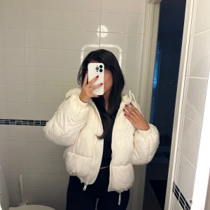 Vit pufferjacka med huva - Säljer en fluffig och oversized vit pufferjacka med huva och dragkedja framtill. Liten fläck på jackan visas på sista bilden