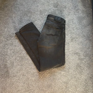 Nudie jeans grim Tim  - DET VITA FLÄKARNA PÅ JEANSEN ÄR SMUTS FRÅN MATTAN                                                                                Märke: nudie jeans grim Tim.                                    Storlek: 31W 32L.                                                          Färg: svart