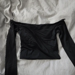 Svart offshoulder topp - Snygg svart offshoulder topp. Toppens material är stretchigt och sitter tight mot kroppen. Långärmad modell med magtröja längd. Blev aldrig använd