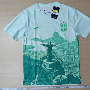 Brasilien fotbollströja - 🇧🇷 Brasilien fotbollströja – Nike Dri-FIT Ljusgrön och vit t-shirt med motiv av Kristusstatyn och Rio de Janeiro.  • Färg: Ljusgrön/vit • Storlek: Finns flera olika storlekar (kontakta för val av storlek) • Skick: Helt ny - aldrig använd