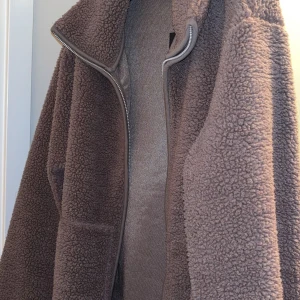 Brun teddyjacka med dragkedja - Mysig brun teddyjacka med hel dragkedja framtill. Jackan har en fluffig och varm känsla, perfekt för kyliga dagar. Etikett och prislapp finns kvar. Storlek Xs/ S 