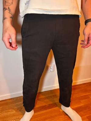 Svarta croppade byxor - Svarta byxor med croppad längd och smal passform. De har fickor på sidorna och är tillverkade i ett mjukt material som känns skönt mot huden. Perfekta för en chill och stilren look.