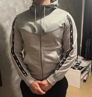 Grå Nike vindjacka med huva - Snygg grå tröja från Nike i mycket bra skick.storlek s men passar även m. Säljs pga inte kommer till användning. Köpt från Zalando 