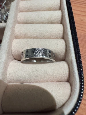 Silvrig ring med fjärilsmotiv - Cool silvrig ring med ingraverade fjärilar och små prickar runt om. Ringen är öppen baktill så den är justerbar i storlek. Perfekt för dig som gillar detaljer och vill ha något unikt på fingret.