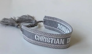 Grå armband från Christian Dior - Snyggt grått armband från Christian Dior med broderad logga i vitt. .