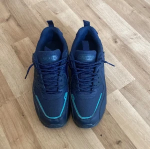 Nike Air Max 90 Cordura blå sneakers - Nike Air Max 90 Cordura sneakers i marinblått med snygga turkosa detaljer. Skorna har slitstark Cordura-textil, klassisk Air Max-sula med synlig luftkudde och rund tå. Perfekt för dig som gillar streetwear och vill ha något som sticker ut.