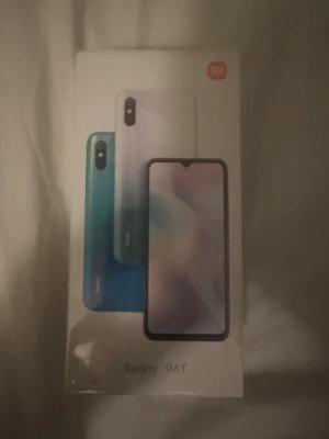 Redmi 9AT - Helt ny Xiaomi Redmi 9AT smartphone i originalförpackning. Android-telefon med stor skärm, lång batteritid och enkel tillgång till Google-appar. Kartongen är obruten och visar inga tecken på slitage. Perfekt för dig som söker en prisvärd och pålitlig mobil.