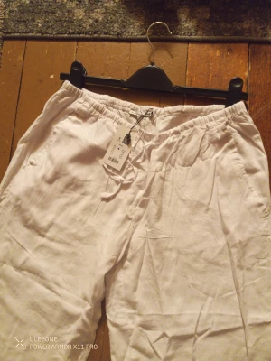 Vita linnebyxor från 157, storlek S - Fräscha vita linnebyxor från 157 med avslappnad passform och elastisk midja med snörning. Byxorna har raka ben och sidofickor, perfekta för chill dagar. Materialet är linne som ger en skön och luftig känsla.