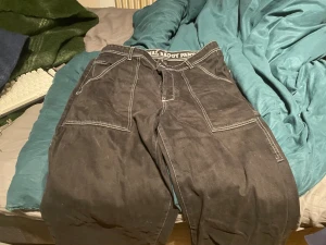 Svarta baggy jeans från Homeboy - Riktigt feta svarta baggy jeans från Homeboy med kontrasterande vita sömmar och stora fickor. Klassisk streetwear-vibe med broderad text 'The Original Baggy Pants' i midjan. Tillverkade i bomull ser ut som en fin suede matrikel för skön känsla och hållbarhet.